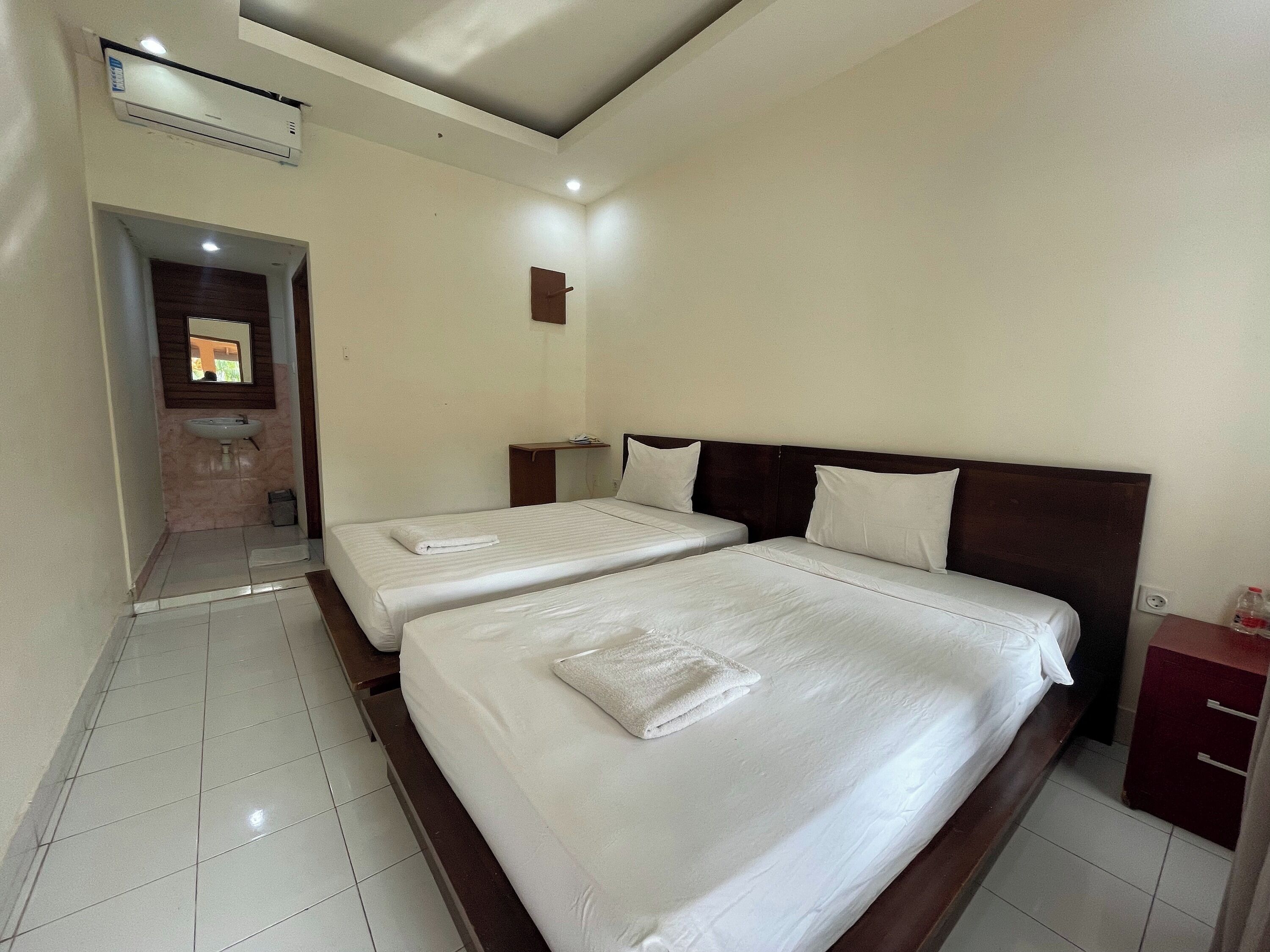 A hotel room with two beds, a bathroom, and a small desk.