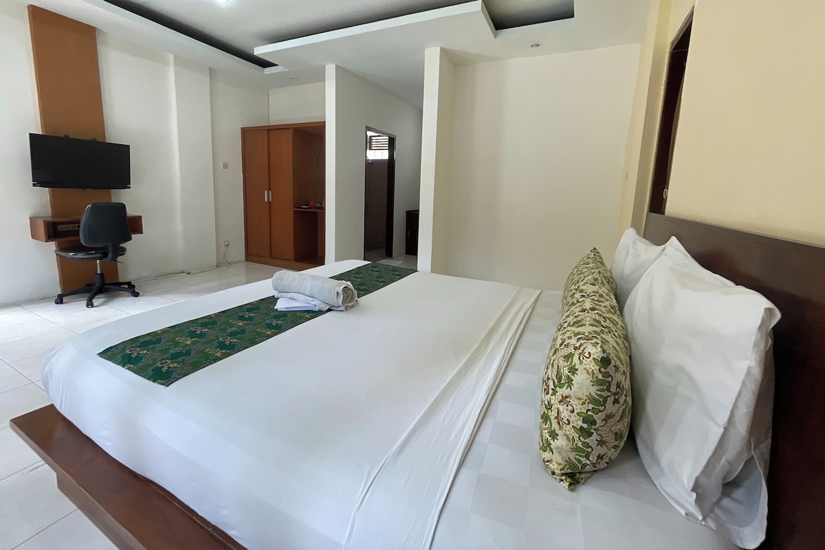 Una habitación de hotel con cama, escritorio, silla, armario y televisor.