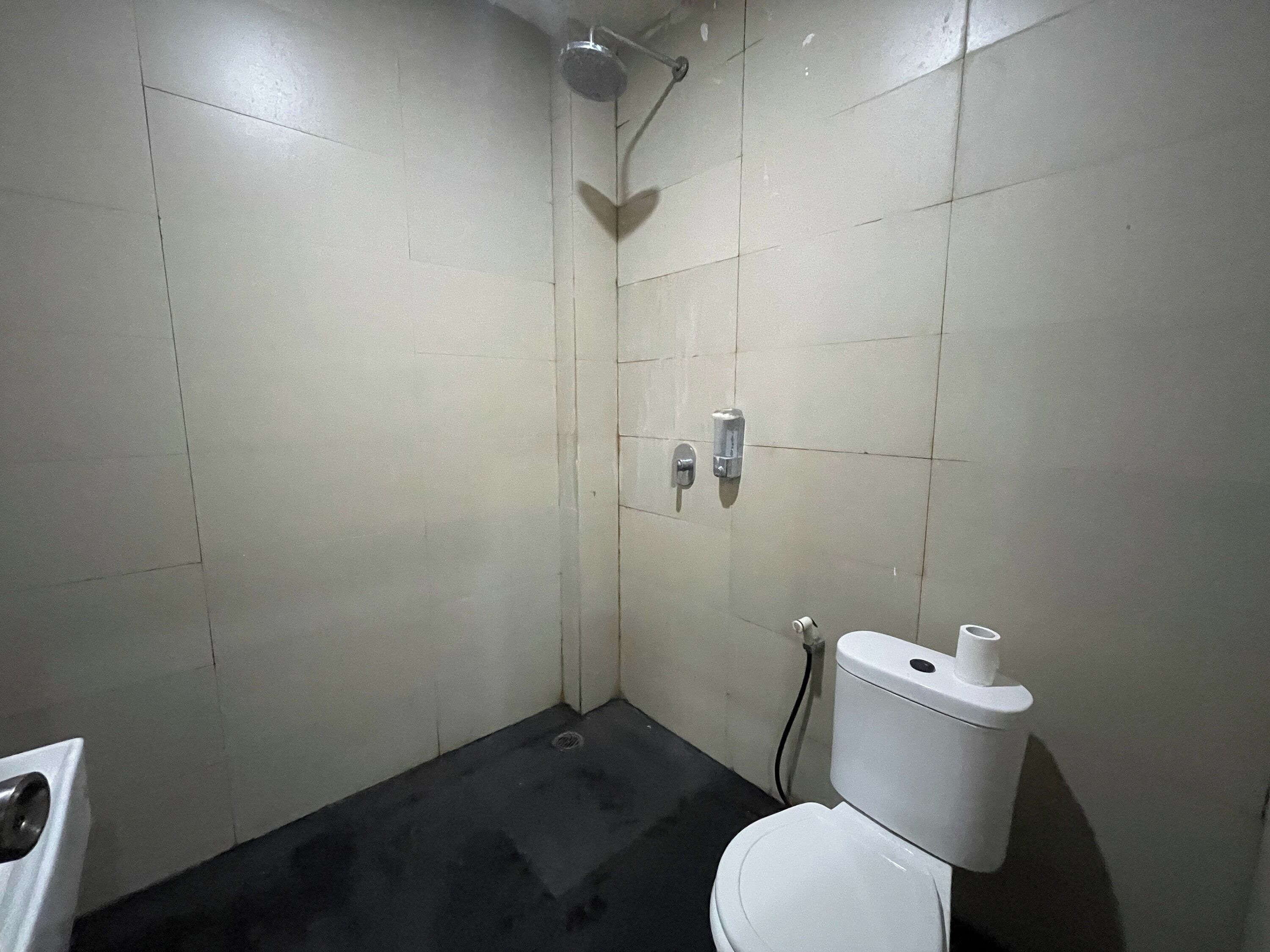 A small, tiled bathroom with a shower, toilet, and a sink.