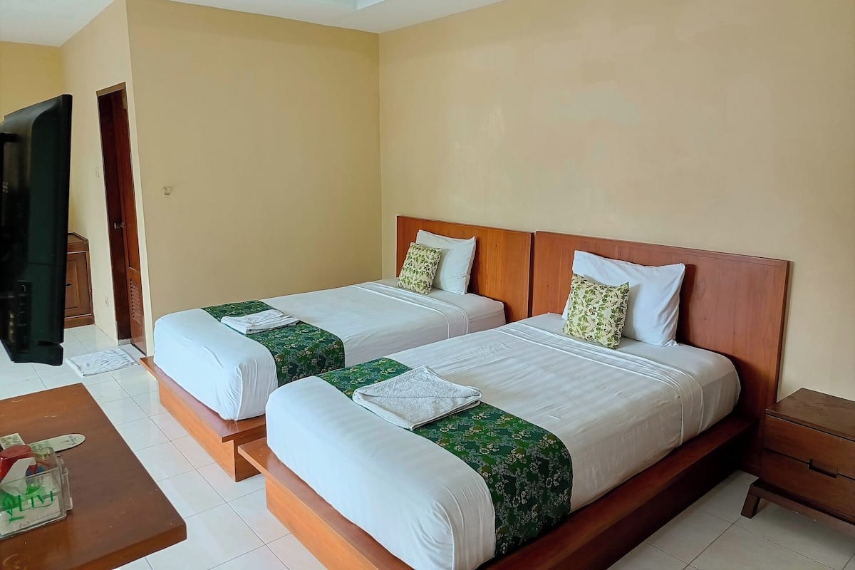 A hotel room with two beds, wooden headboards, and a wooden nightstand.