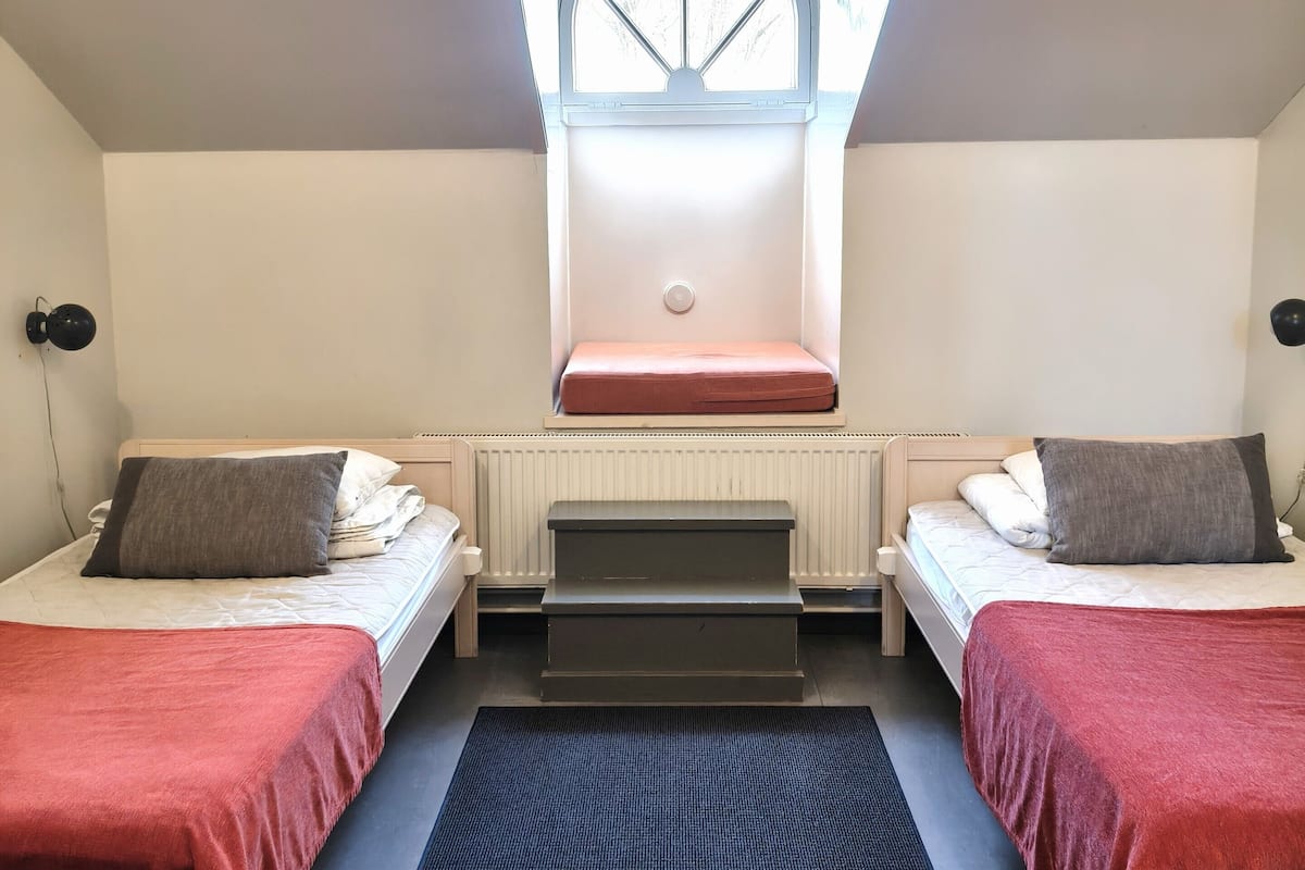 A room with two beds, a skylight, a small staircase, and a radiator.