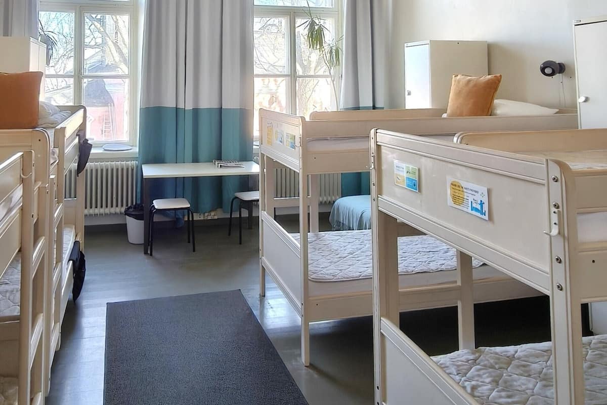 A room with bunk beds, a desk, and a window with curtains.
