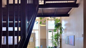 A modern interior with a staircase, a reception desk, and a seating area with tables and chairs. - Hostel Suomenlinna (Helsinki)