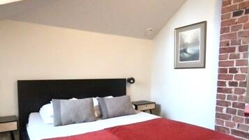 Una habitación de hotel moderna con una cama grande, un muro decorativo de ladrillo y un cuadro en la pared.