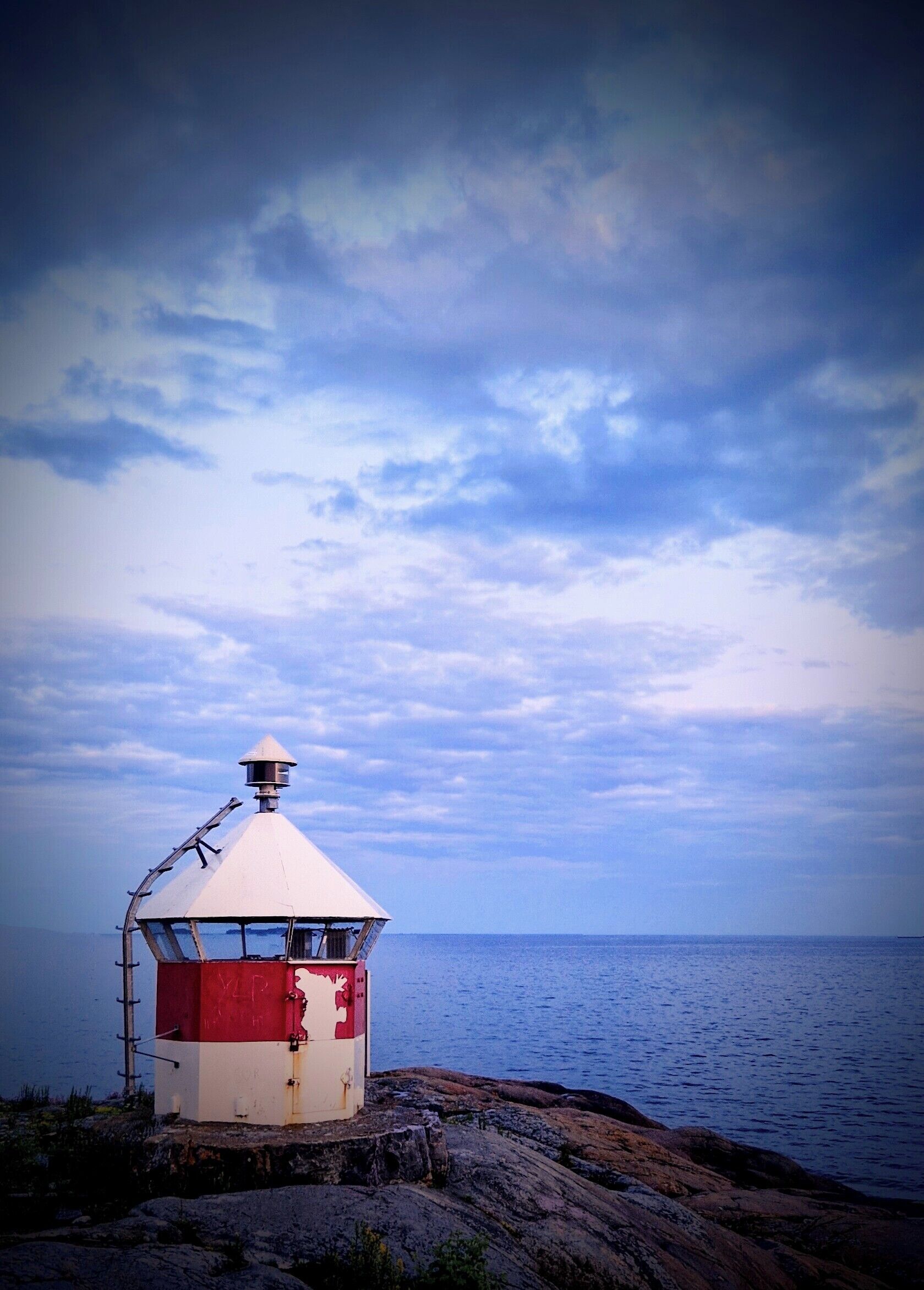 Un faro sobre una costa rocosa con una vista despejada del mar y el cielo.