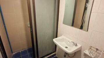Et badeværelse med bruser, vask og toilet.