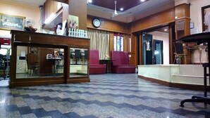 A hotel lobby with a check-in counter, seating area with chairs, a fan, a clock, and a patterned floor. - Huahin Euro City Hotel (Hua Hin)