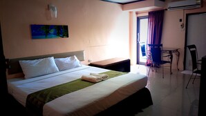 A hotel room with a bed, a desk, a chair, and an air conditioning unit. - Huahin Euro City Hotel (Hua Hin)