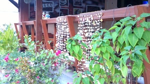 A covered outdoor area with a large planter with water lilies, potted plants, and a wooden fence with hanging decorations. - Huahin Euro City Hotel (Hua Hin)