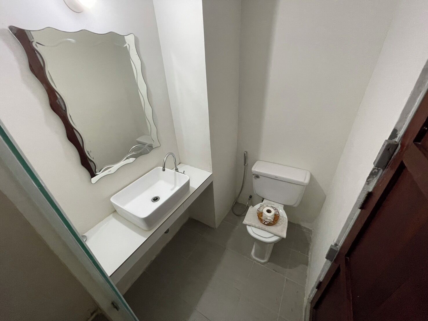 Un baño pequeño con un lavamanos blanco, un inodoro y un espejo con marco decorativo.