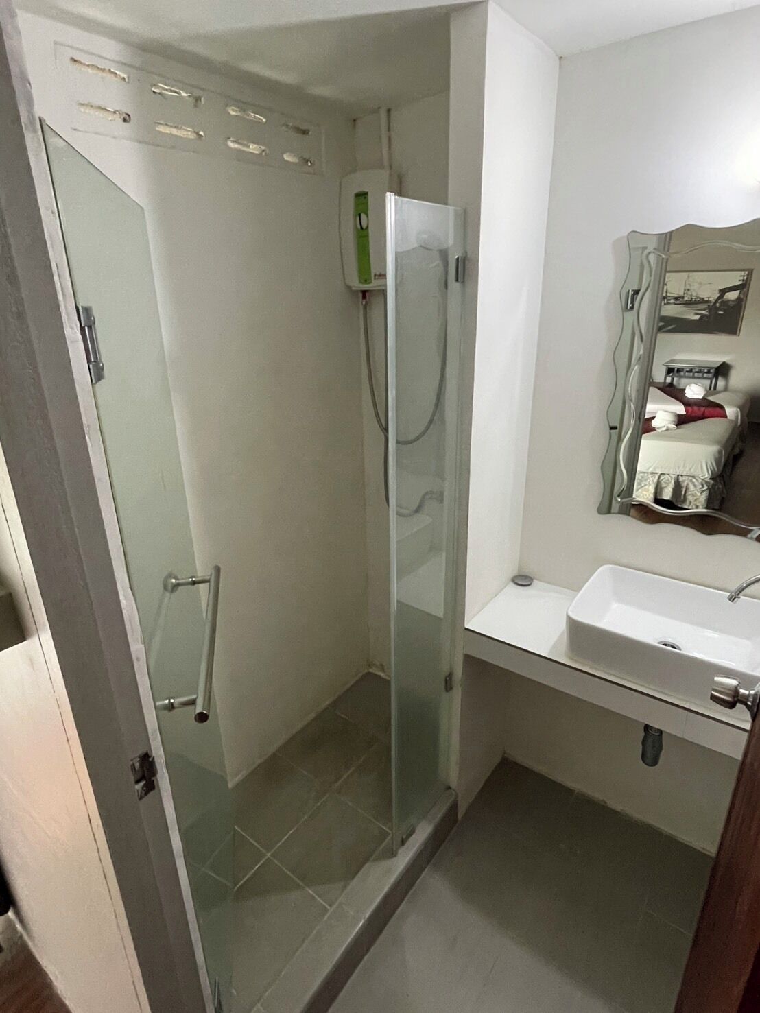 A bathroom with a glass shower enclosure, a sink, and a mirror.