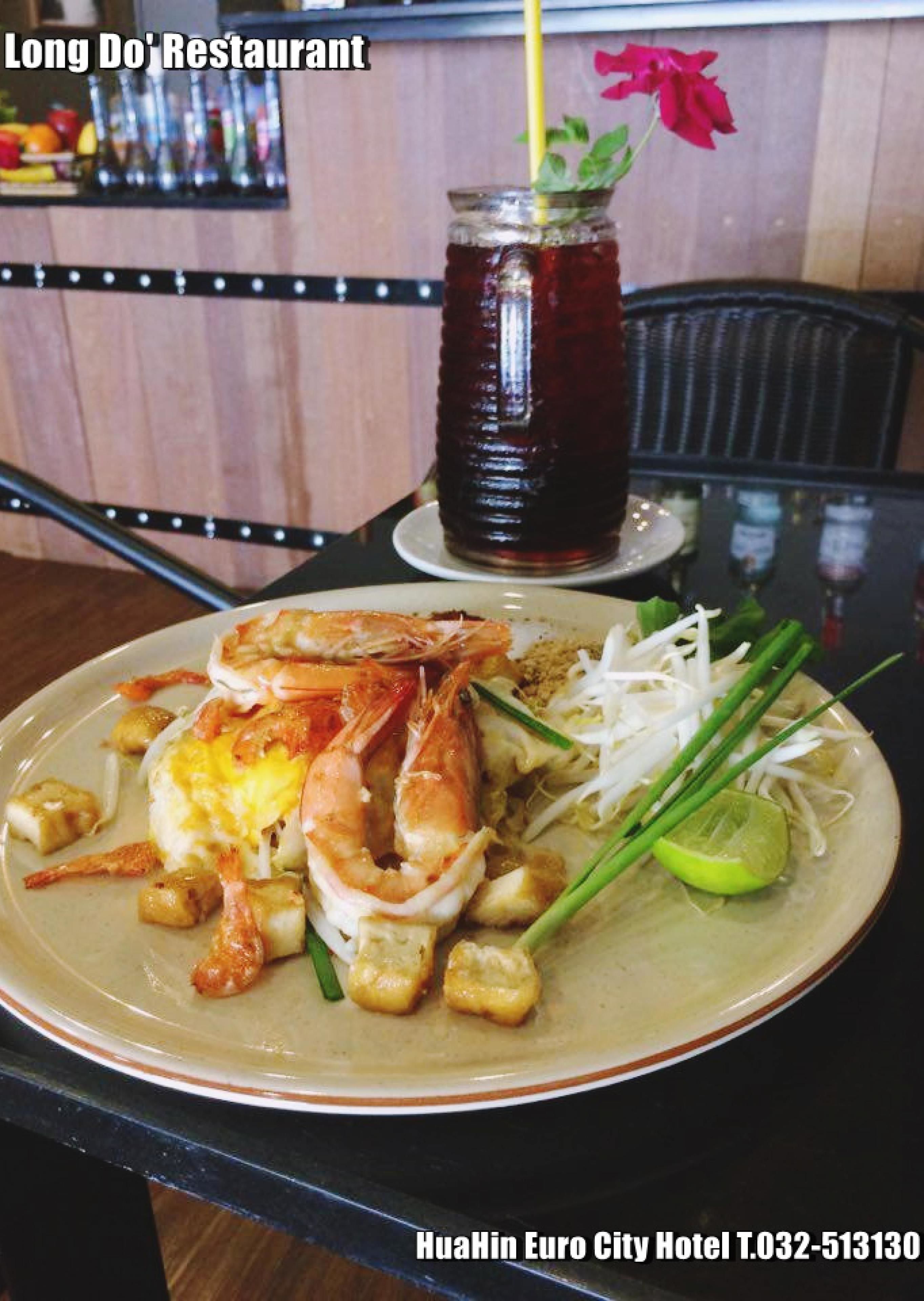 A plate of food with shrimp, egg, and bean sprouts, accompanied by a drink in a jar.