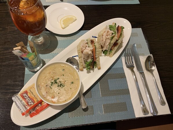 A meal consisting of soup, a sandwich, and a glass of iced tea on a table with a placemat.
