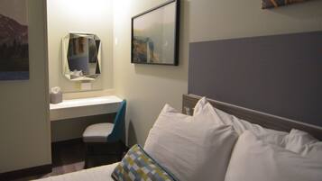 Una habitación de hotel con cama, escritorio, silla y espejo.