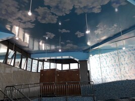 Un interior moderno con un mural en el techo, ventanas grandes y una escalera.