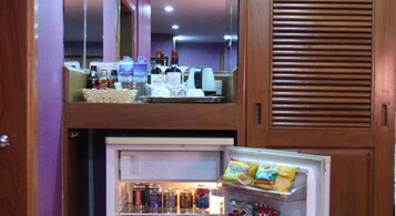 Una cocina compacta con un refrigerador lleno de aperitivos y bebidas, un microondas y una cafetera.