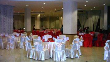 A banquet hall with round tables and chairs, some covered in red and others in white.