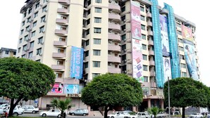 A multi-story hotel with balconies, a prominent sign reading "EXCEL TREASURE HOTEL," and several large advertisements on the facade. - Excel Treasure Hotel (Yangon)