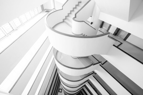 A modern, multi-level interior with a prominent spiral staircase, clean lines, and a minimalist design.