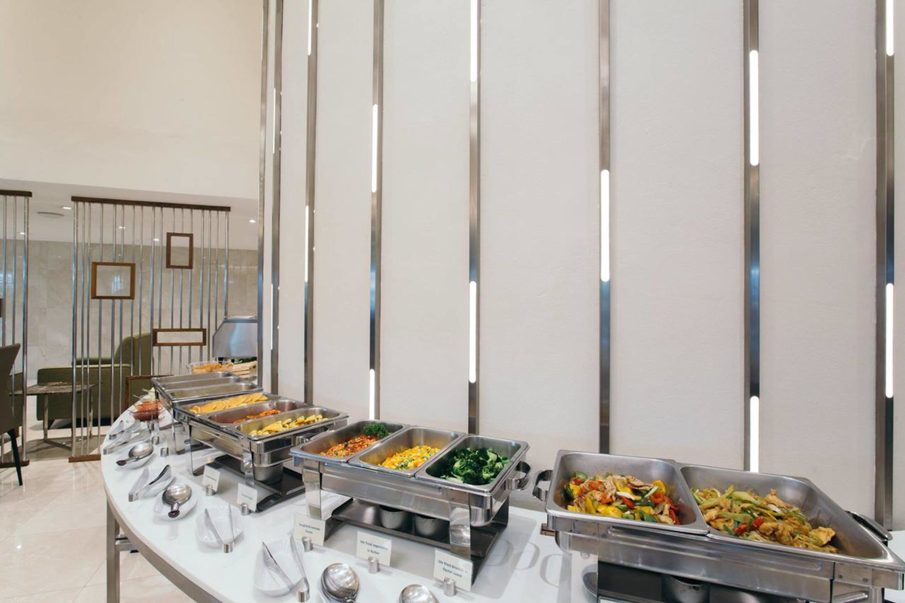A buffet setup with various food stations, including trays of vegetables, meats, and other dishes.