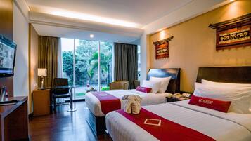 A hotel room with two beds, a desk, a chair, and a TV.