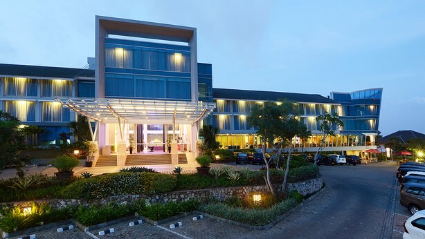 A modern hotel with a glass facade, outdoor seating, and a landscaped garden.
