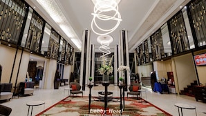 A spacious lobby with a modern chandelier, seating areas, and a reception desk.