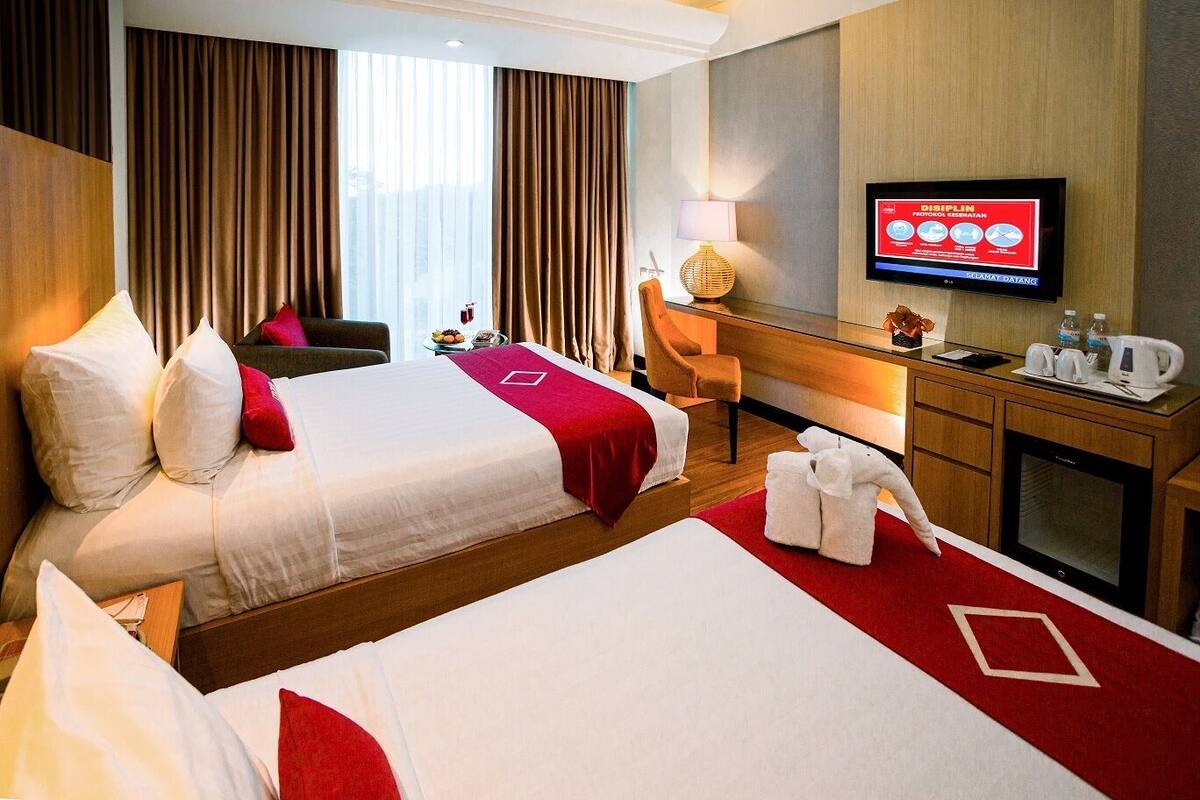 Une chambre d’hôtel avec deux lits, un bureau, une télévision et une vue sur l’extérieur.
