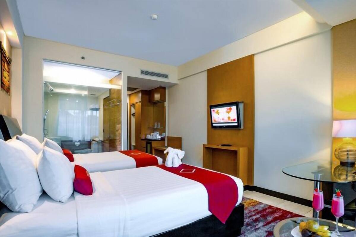 Une chambre d’hôtel avec un lit, une télévision, une petite table avec des boissons et un miroir.