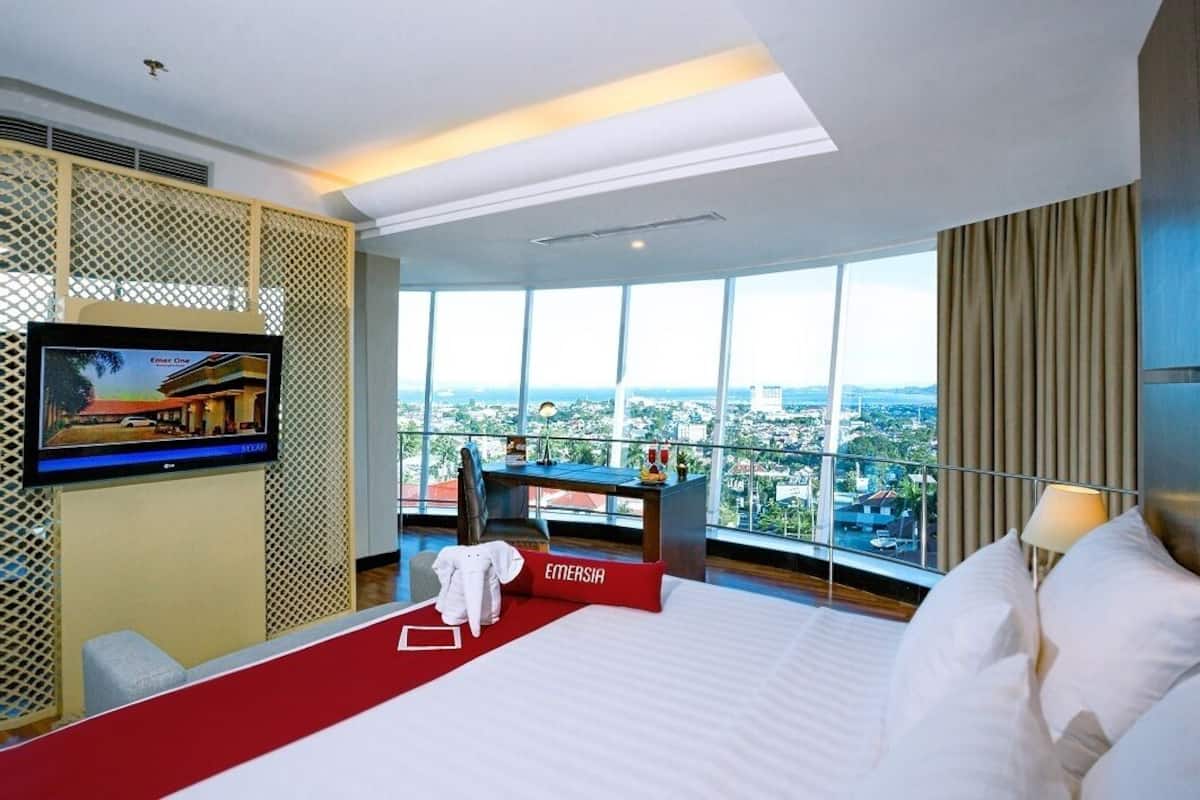 Une chambre d’hôtel avec un grand lit, un bureau, une télévision et une vue sur la ville.
