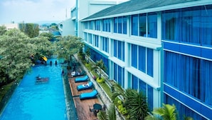 A hotel with a swimming pool, lounge chairs, and a view of the surrounding area.