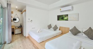 A hotel room with two beds, a small desk, a mirror, an air conditioner, and a wall-mounted artwork. - Sawasdee Coco (Rayong)