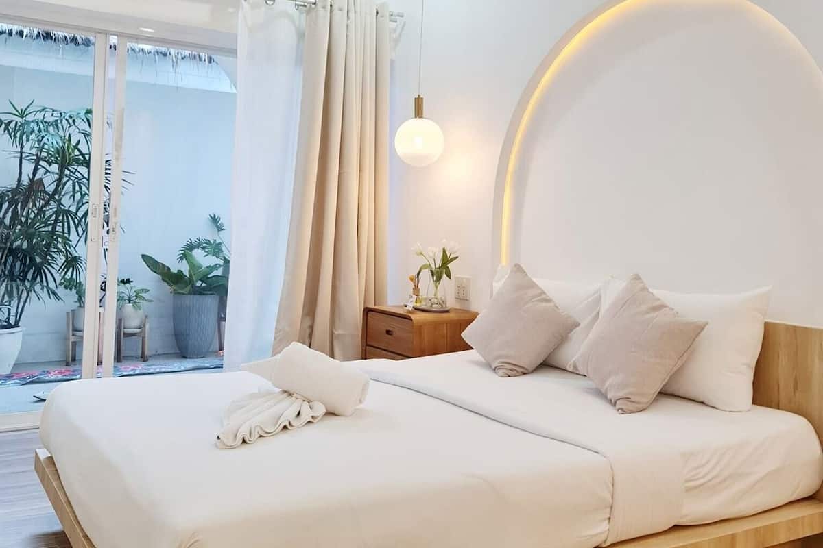 A modern bedroom with a bed, bedside table, and a view of the outside.
