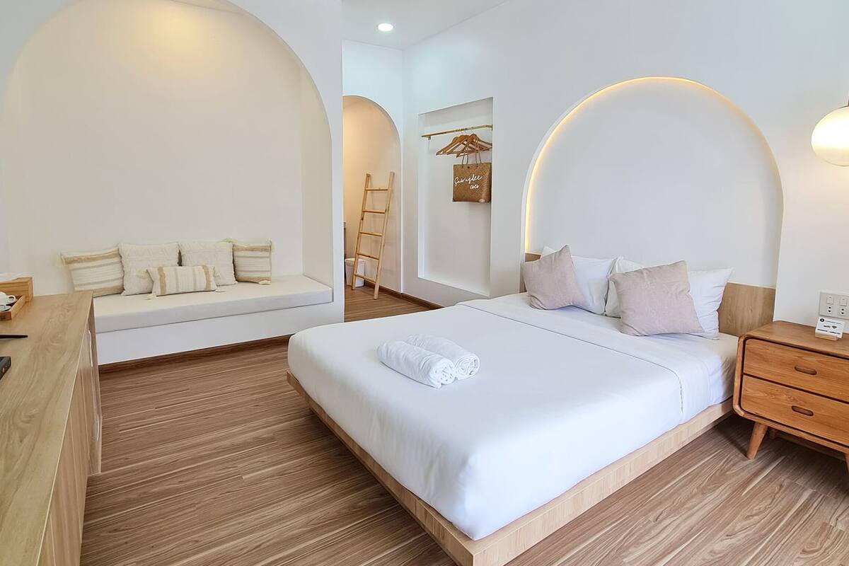 A modern bedroom with a large bed, bedside tables, a desk, and a TV.