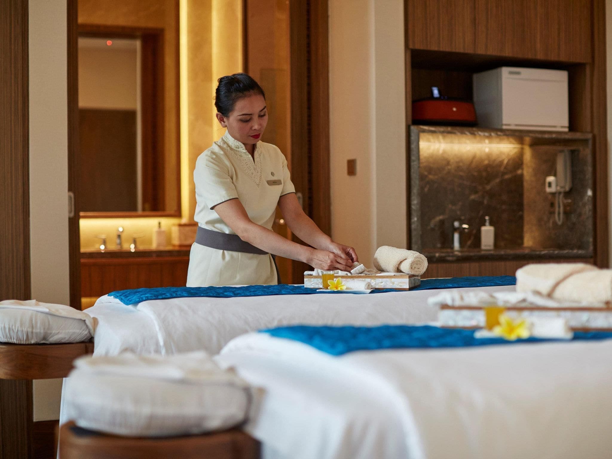 A hotel room with a massage table, towels, and toiletries.