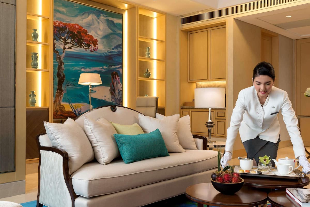 A well-lit living room with a sofa, a painting, and a tray with tea set.
