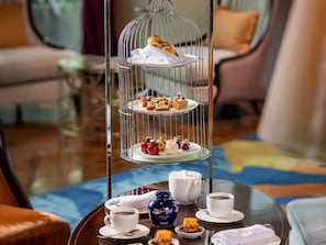 A three-tiered dessert stand with pastries and a teapot on a table. - Raffles Jakarta (Jakarta)