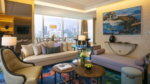 A modern hotel room with a sofa, armchairs, a coffee table, and a painting on the wall. - Raffles Jakarta (Jakarta)