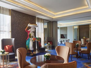 A hotel lobby with a statue, seating arrangements, and a large window. - Raffles Jakarta (Jakarta)