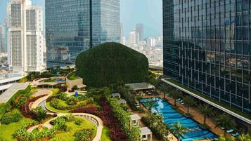 Un hotel moderno con jardín en la azotea, piscina y vistas de edificios altos aledaños.
