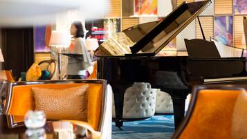 Un piano de cola en el vestíbulo de un hotel, con asientos lujosos y una alfombra estampada.