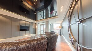 Un intérieur moderne avec un canapé aux lignes courbes, une grande horloge murale et un téléviseur fixé au mur.