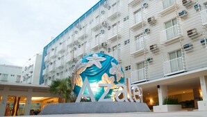 A hotel with a large decorative sculpture in front, multiple balconies, and a modern architectural design.
