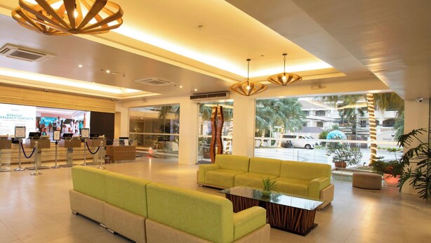 A hotel lobby with a reception desk, seating area, and large windows overlooking the street.