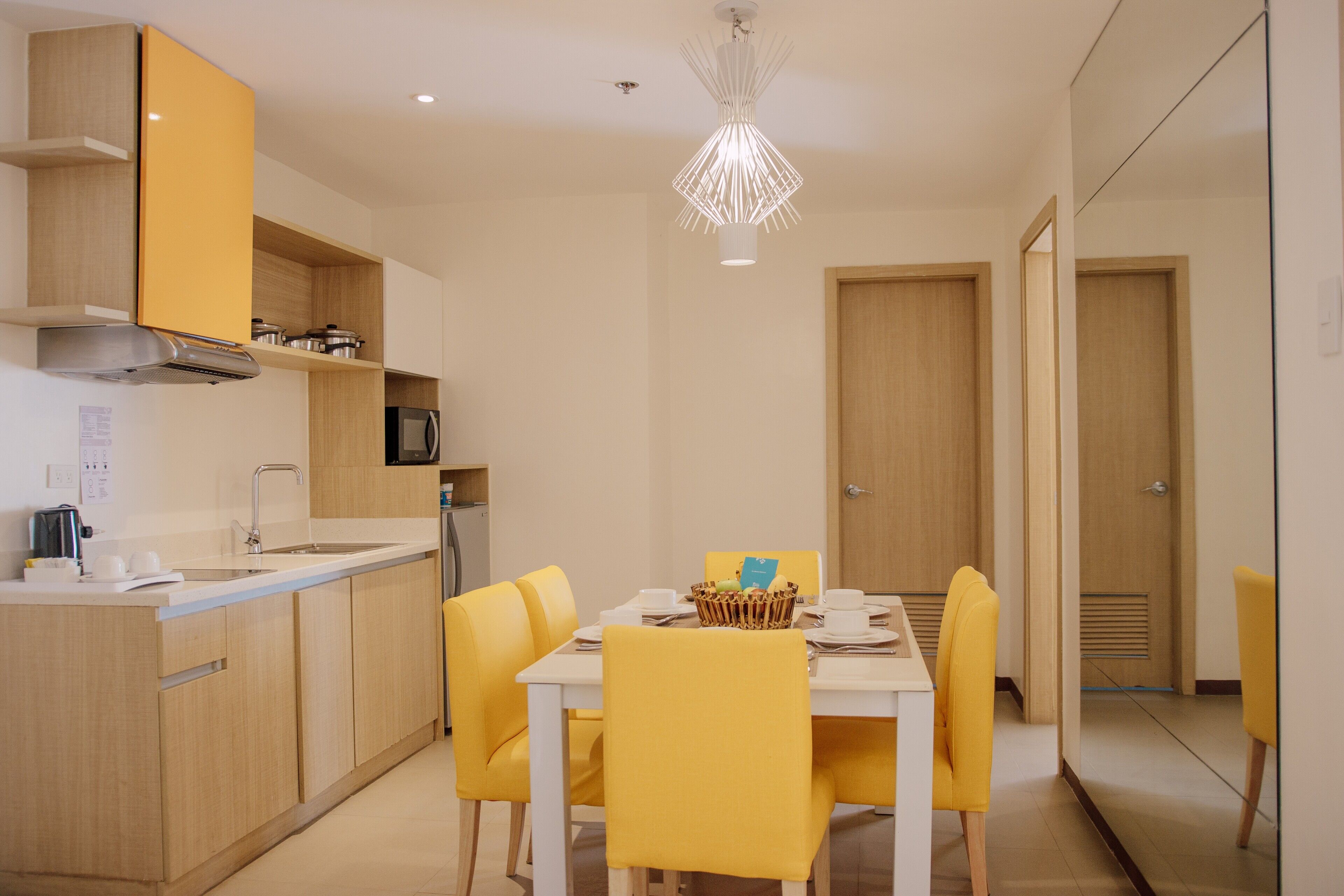 Una cocina moderna con armarios amarillos, una encimera blanca y un comedor con sillas amarillas y una mesa blanca.