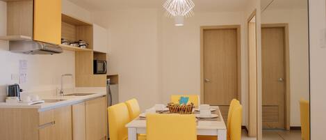 Una cocina moderna con armarios amarillos, una encimera blanca y un comedor con sillas amarillas y una mesa blanca.