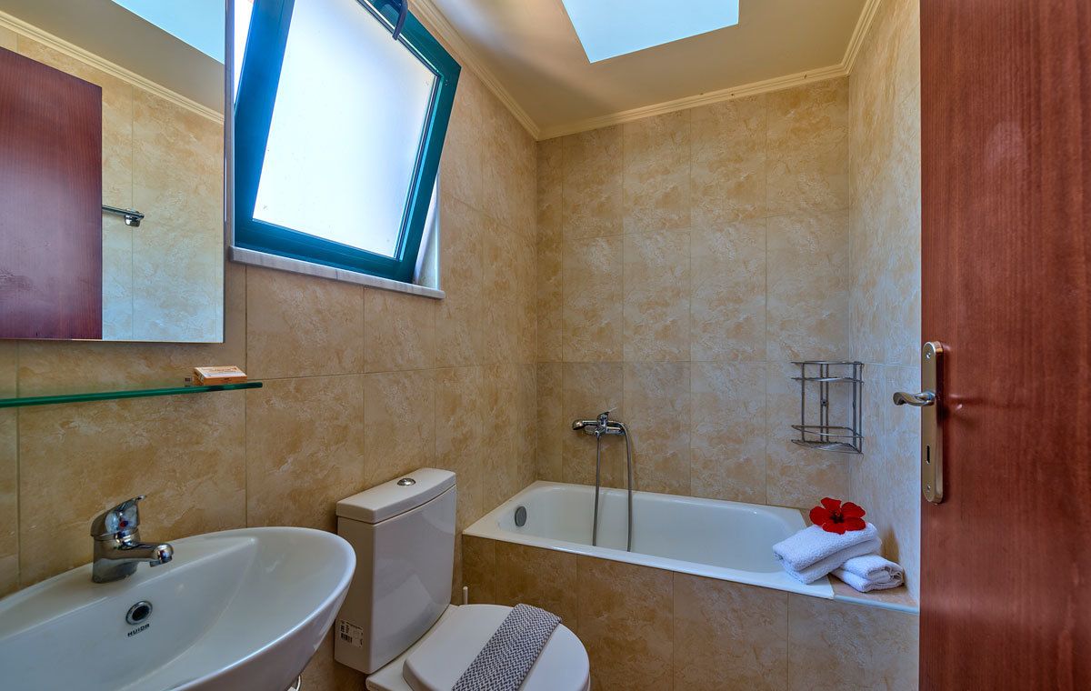Een badkamer met een bad, toilet, wastafel en dakraam.