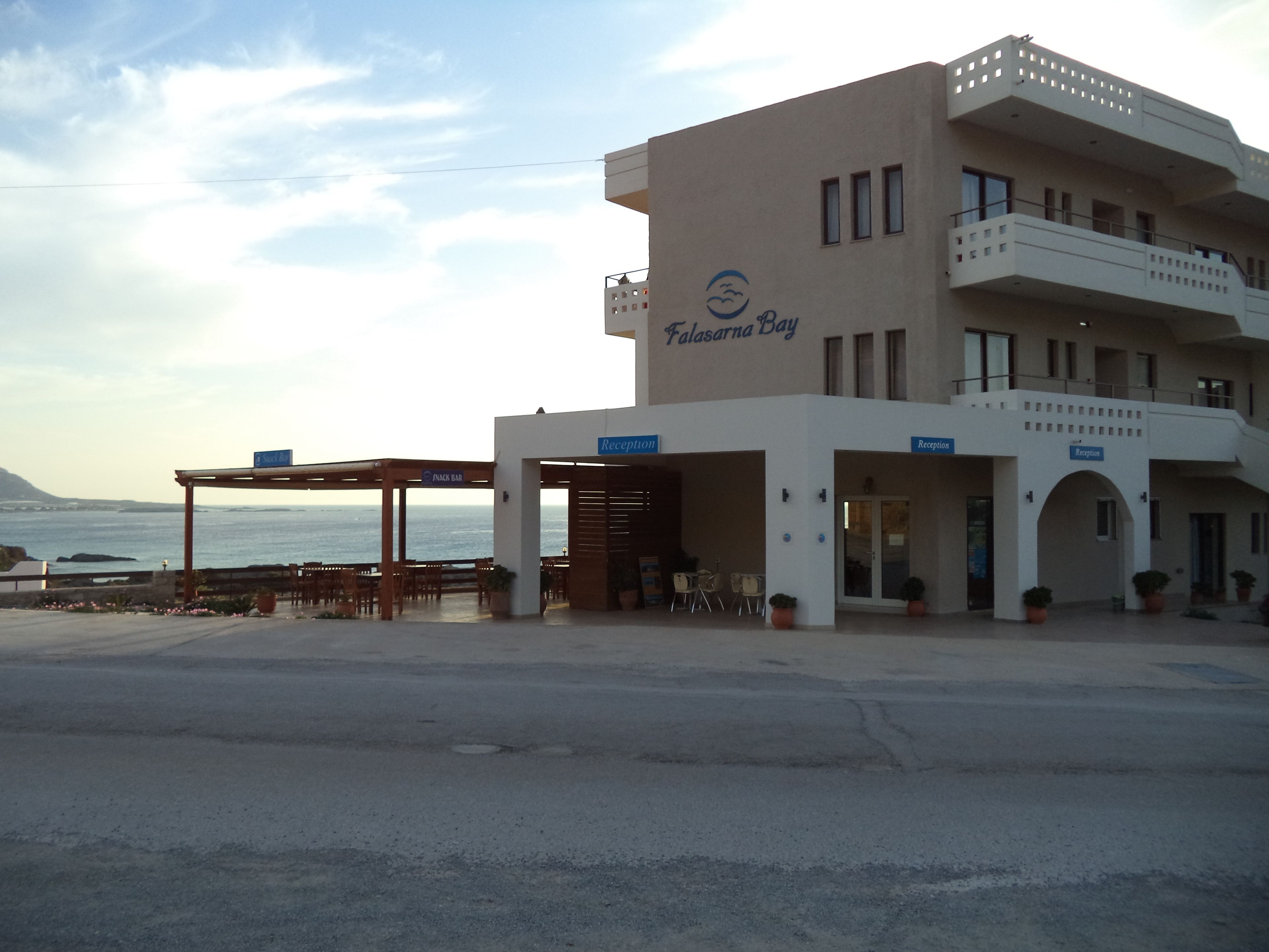 A building with a reception area, a snack bar, and outdoor seating by the sea.