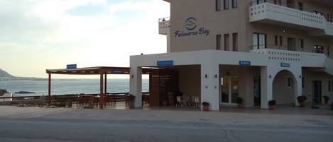 A building with a reception area, a snack bar, and outdoor seating by the sea.