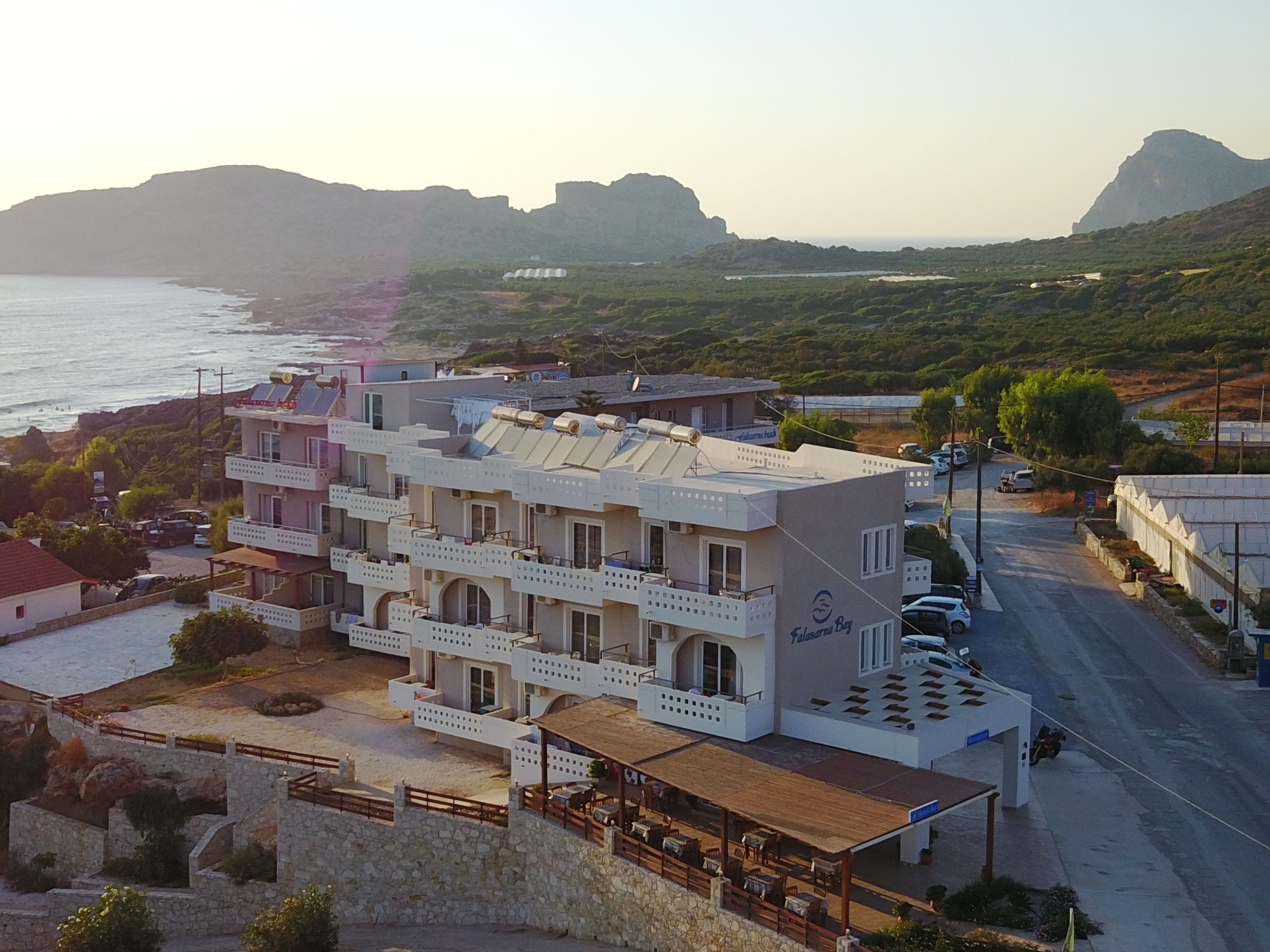 Un hotel de varios pisos con balcones, un área de restaurante y vistas al mar y a las colinas.